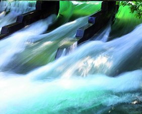 Wasserfall mit türkisfarbenem Wasser und grün schimmernden Lichtreflexen