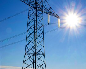 Strommasten gegen blauen Himmel und Sonne fotografiert