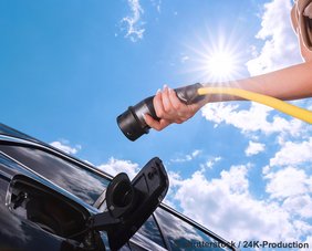 Symbolbild: ladestecker und E-Auto mit offener Ladebuchse, von unten gegen Sonne und blauen Himmel fotografiert