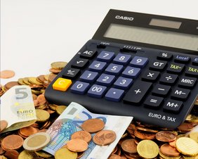 Taschenrechner mit vielen Münzen und einigen Euroscheinen