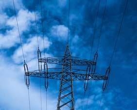 Ein Strommast von unten gegen den blauen Himmel fotografiert.