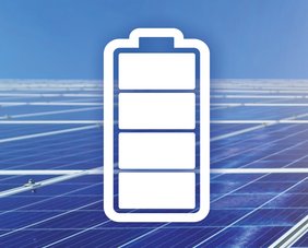 PV-Anlage unter blauen Himmel, in der Mitte des Bildes ein weißes Stromspeicher-Symbol