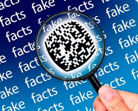 die Wörter fake und facts werden von einer Lupe vergrößert