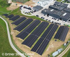 Luftaufnahme des Firmengwelandes des Autohaus Ortner mit großer PV am Dach und Freiflächen-PV daneben