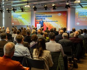 Foto der Veranstaltung "Innoforum ErneuerbareEnergie" mit Sprecher auf der Bühne und Publikum von hinten